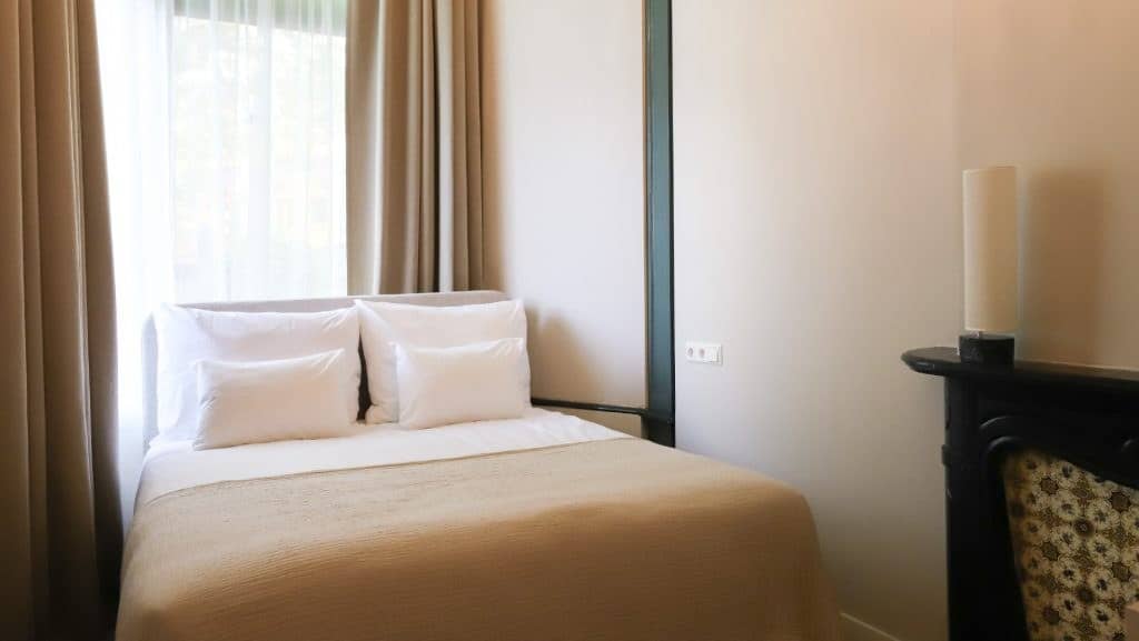 Hotelkamer van DAM Residence met een klassiek bed en hoge ramen